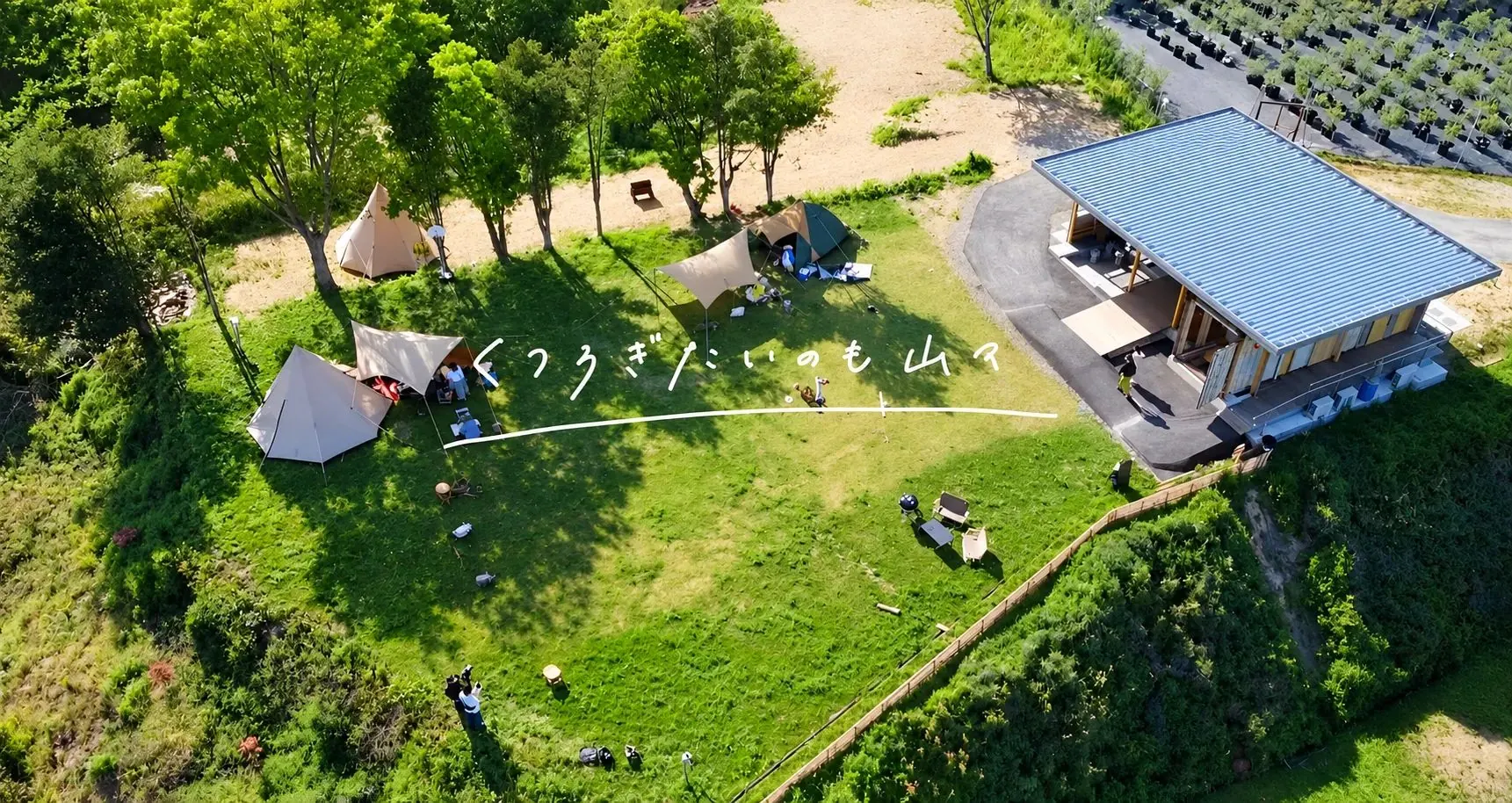 上から見たキャンプ場。芝生にテントが並び、横に木の建物がある