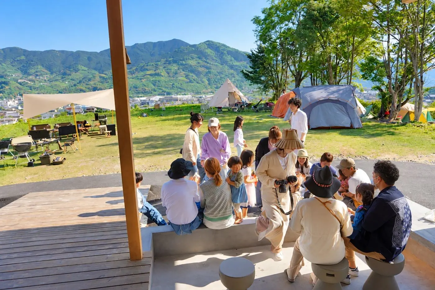 緑の芝生と山を背に、テラスに集まって笑う親子たち