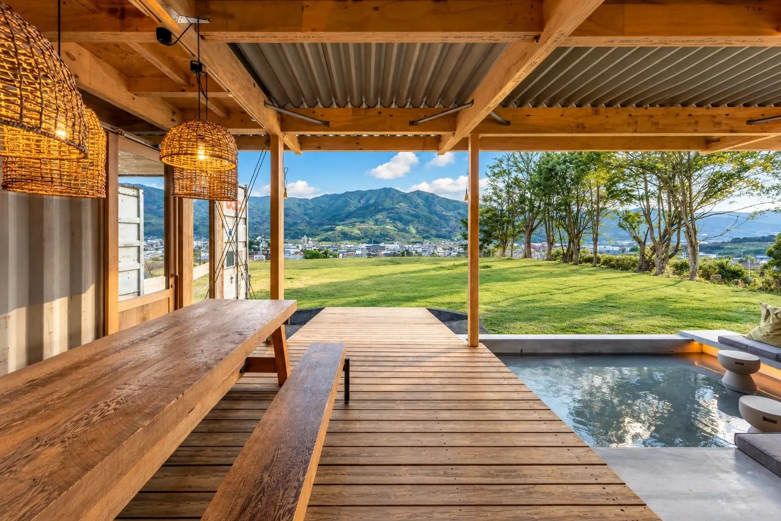 木の屋根のテラスから、緑の芝生と山並みを見渡す